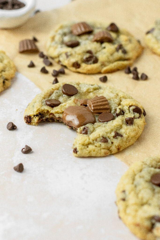 Chocolate chip cookies with mini Reese's on top with a bite taken out of it.