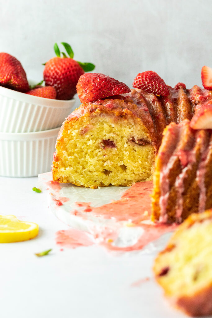 Bundt cake cut in half and looking at the inside with a bowl of strawberries on the side.