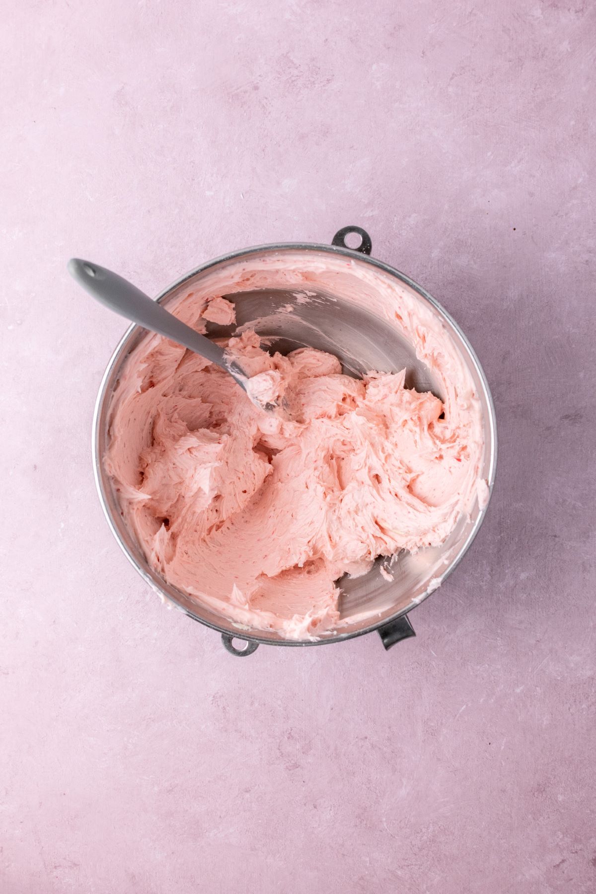 Strawberry frosting in a stainless steel mixing bowl.