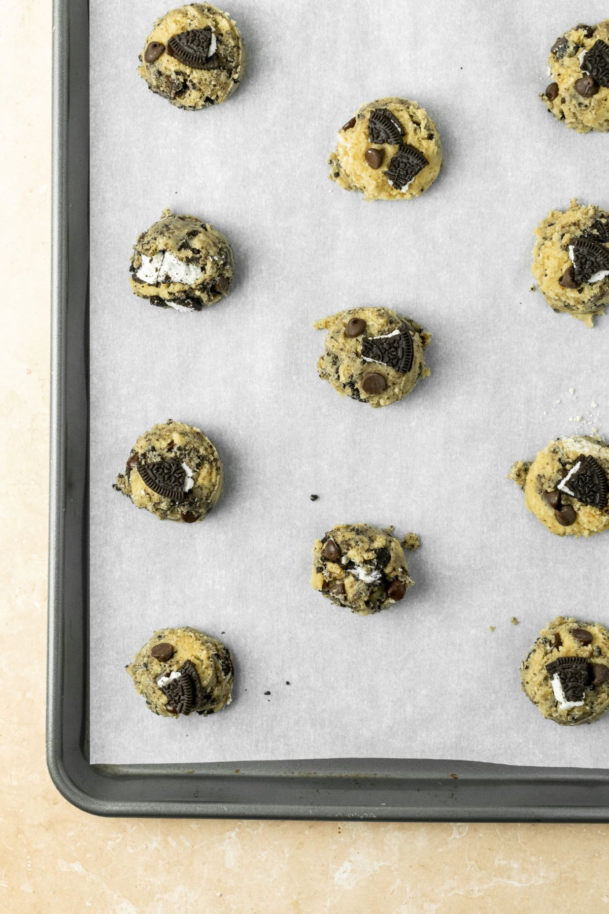 Cookie dough balls on a parchment lined baking pan.