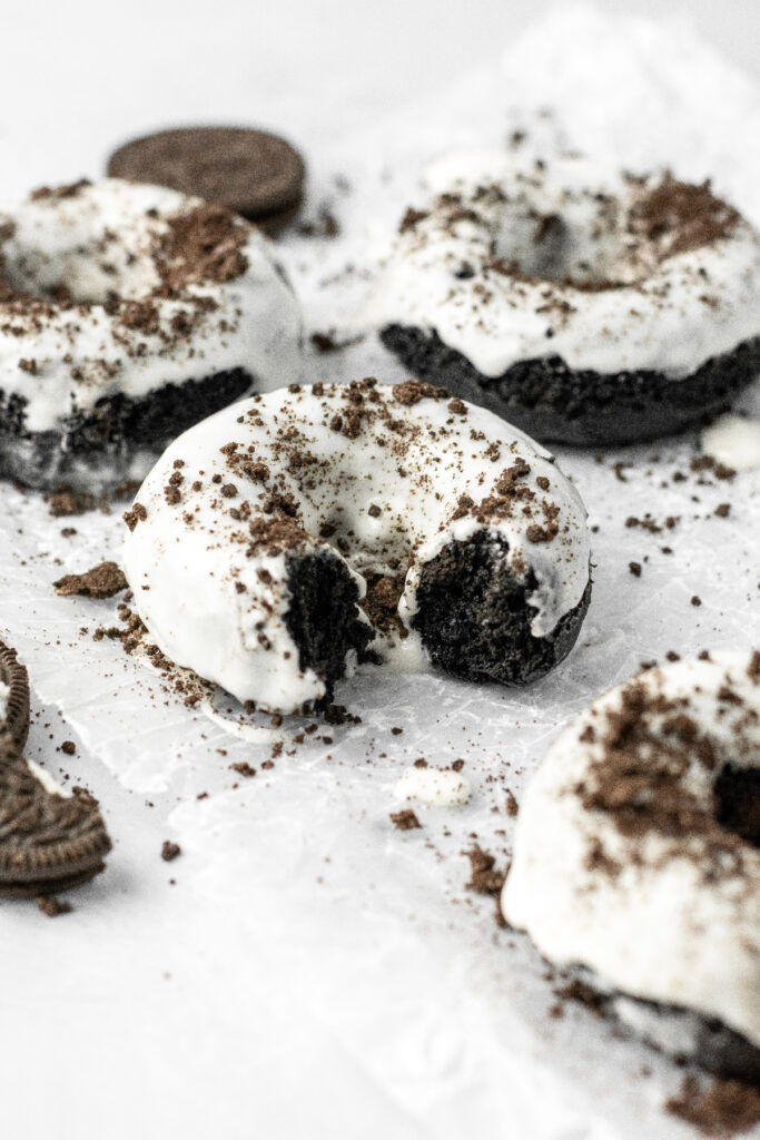 Chocolate donuts with oreo cookie glaze on top with a bite taken out of it.