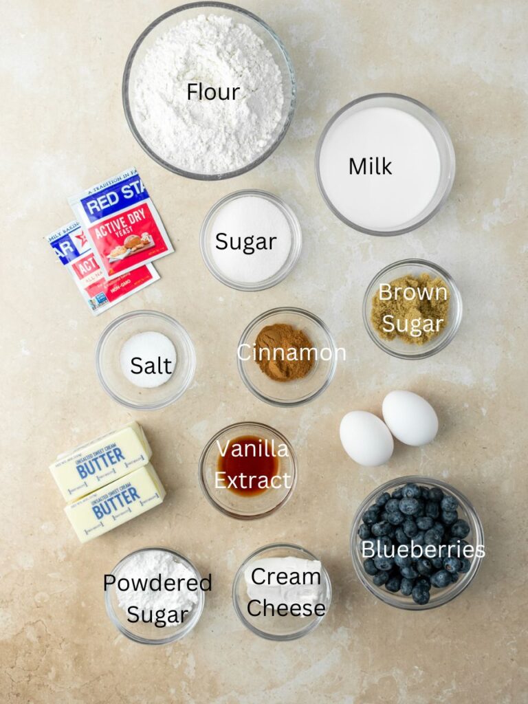 Ingredients: flour, sugar, milk, yeast, salt, cinnamon, brown sugar, butter, vanilla, eggs, blueberries, cream cheese, and powdered sugar.