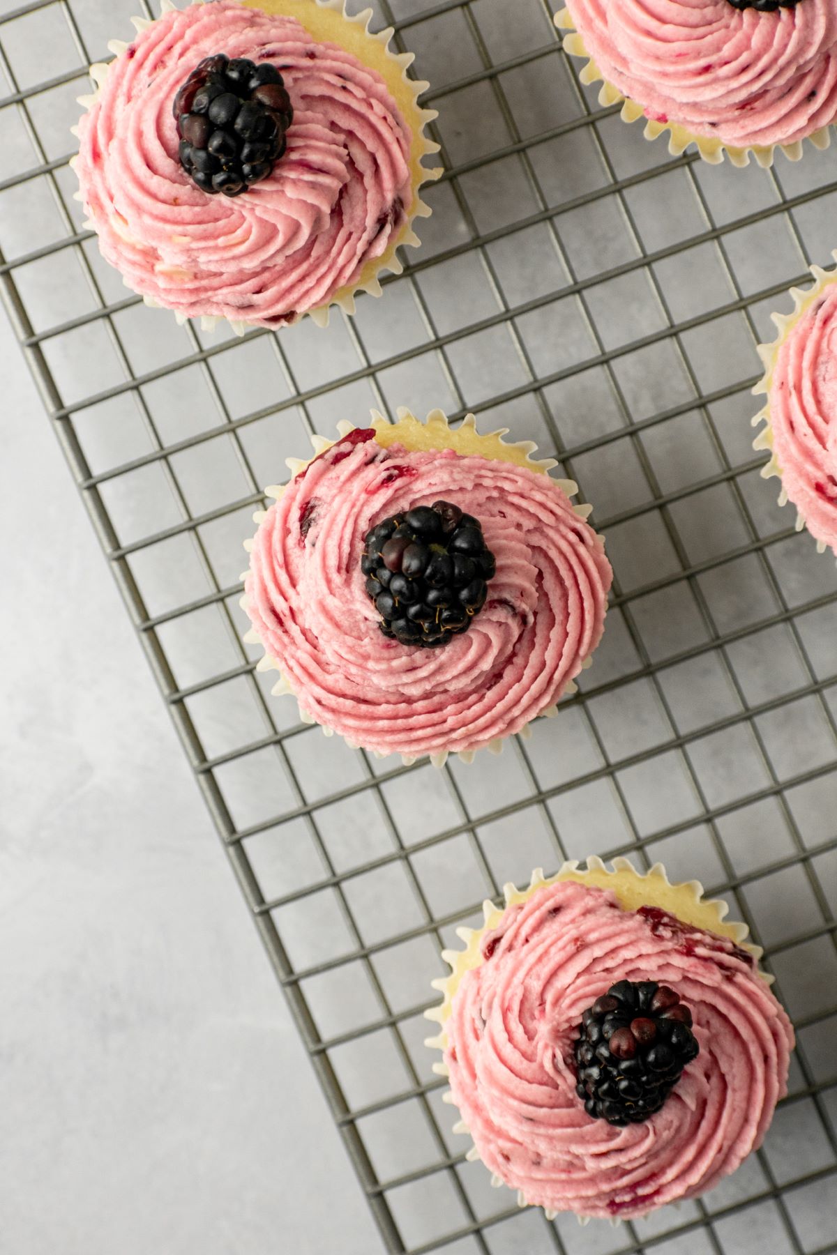 Blackberry frosting with a fresh berry on top of a cupcake.