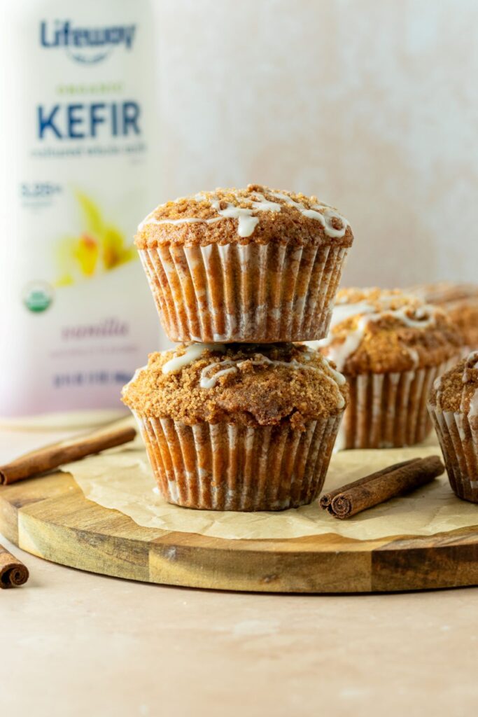 Stacked muffins on top of a brown cake plate with a bottle of kefir milk in the background.