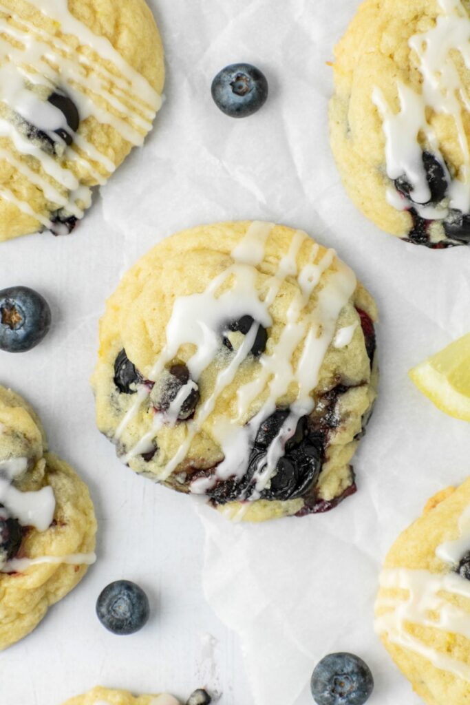 Lemon blueberry cookies with a glaze on top and blueberries on the side.