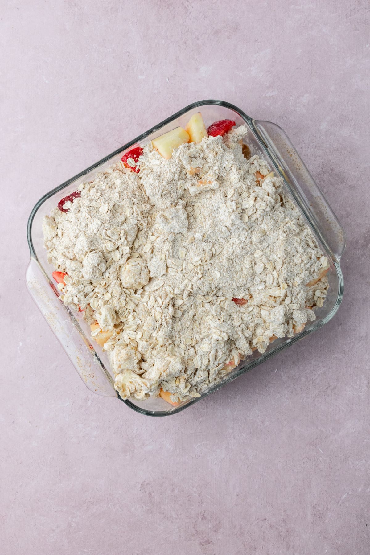 Oat streusel sprinkled over the top of fruit in a baking pan.