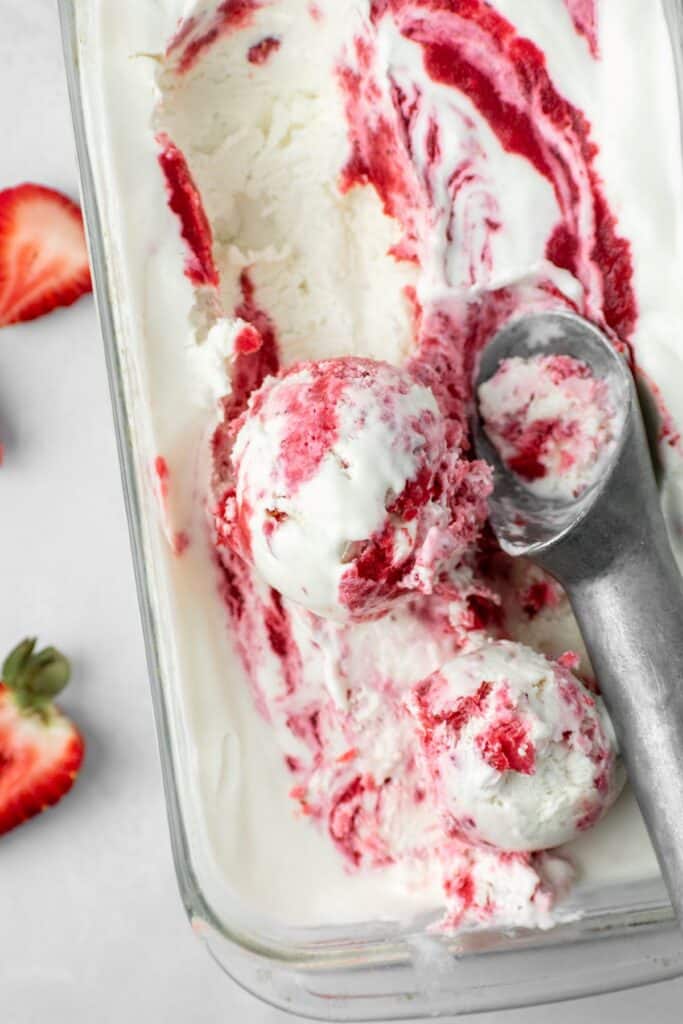 Strawberry swirl ice cream with a silver ice cream scoop.