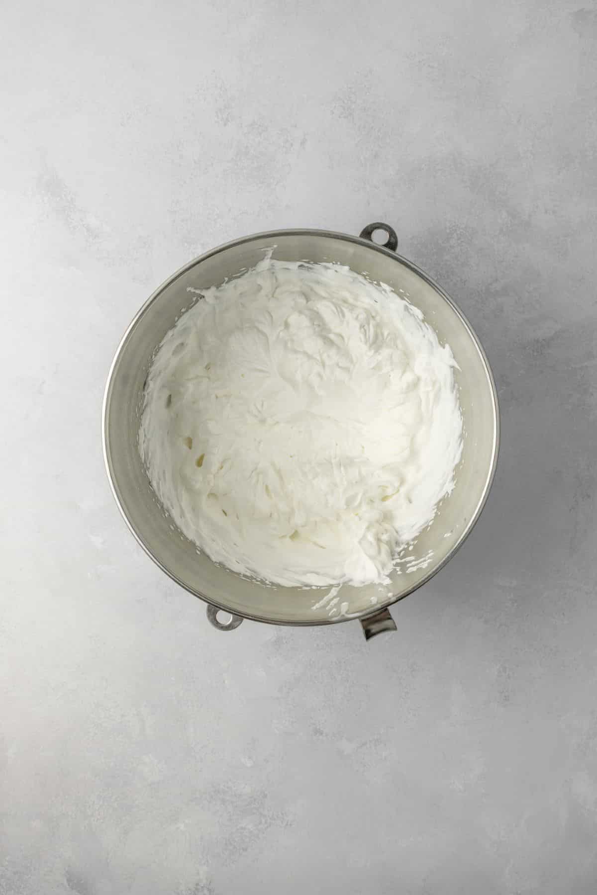 Whipped cream in a stainless steel bowl.