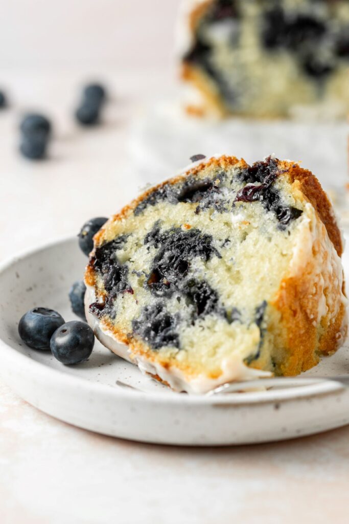 A slice of blueberry pound cake on a white plate.