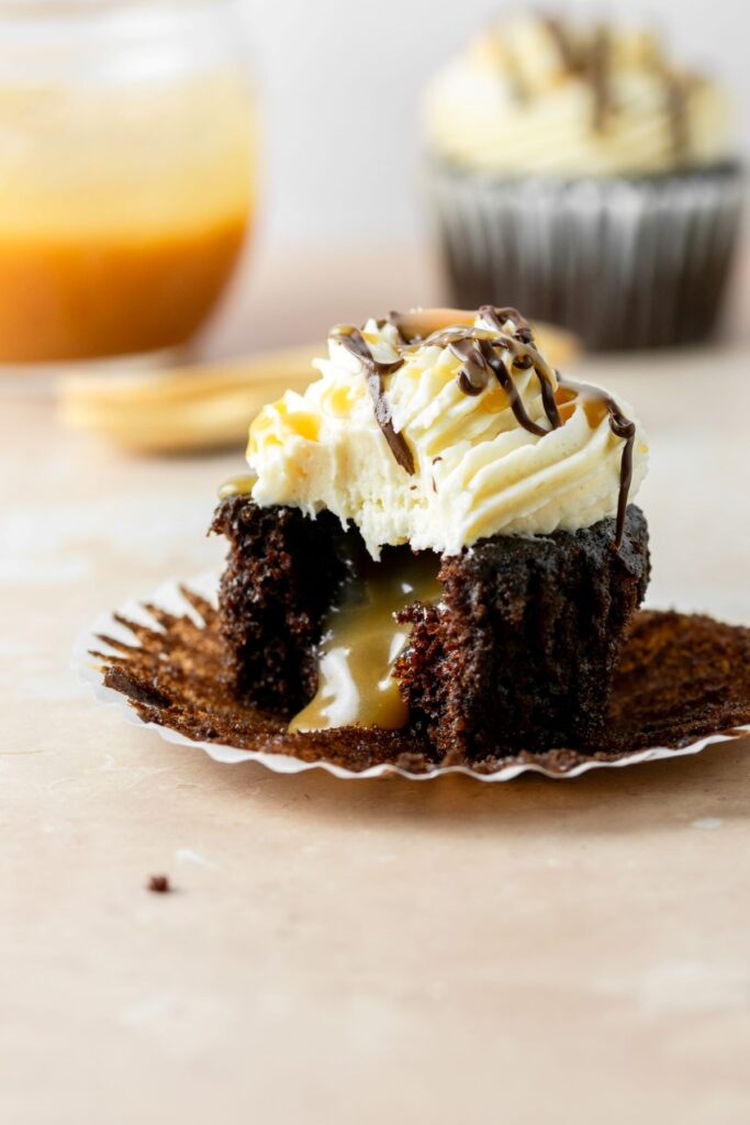 Chocolate caramel cupcake with caramel filling, frosting, and chocolate drizzle on top.