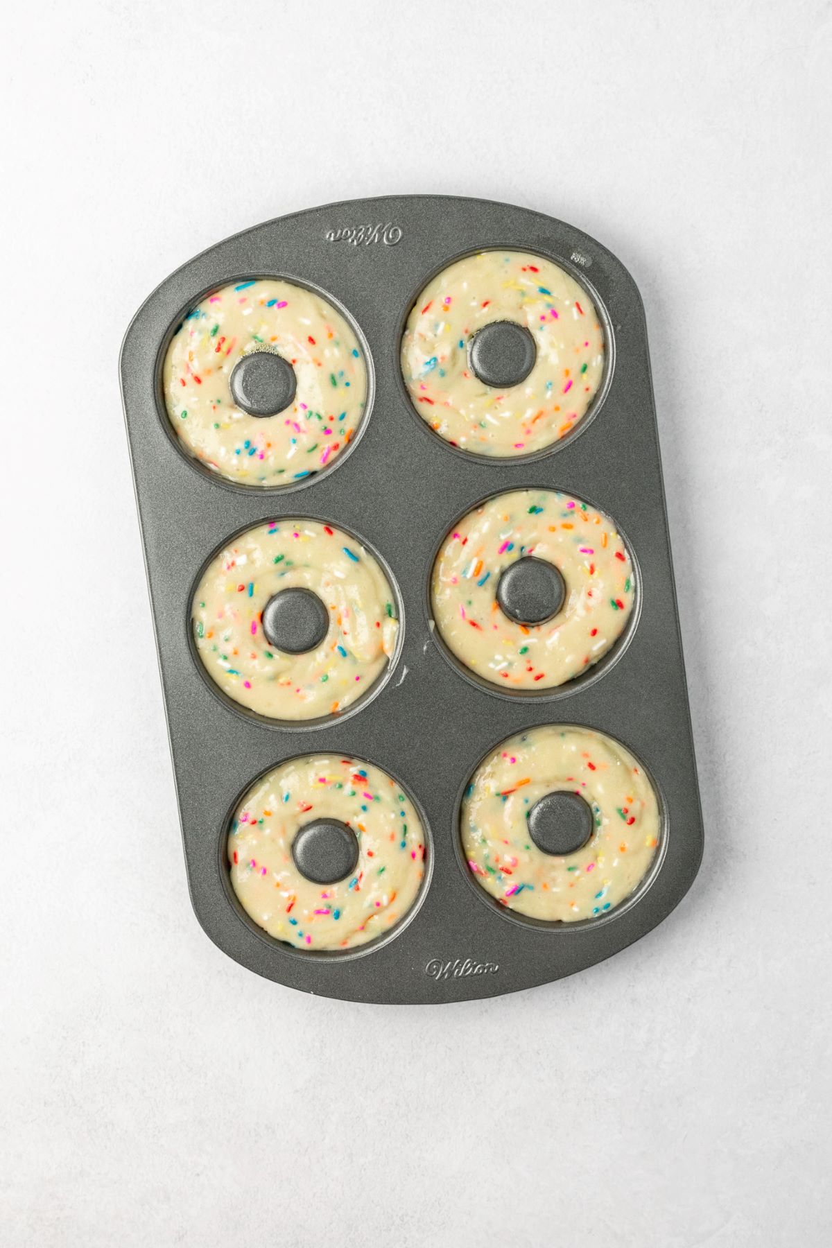 Donut pan with batter in each donut cup.