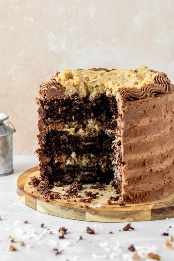German chocolate layer cake with chocolate frosting and coconut pecan frosting. It's sitting on a brown cake plate.