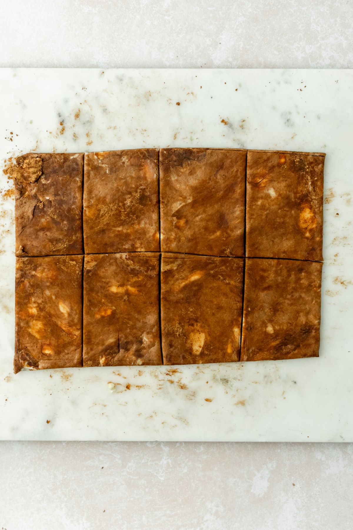 Chocolate dough cut into 8 rectangles on a marble board.