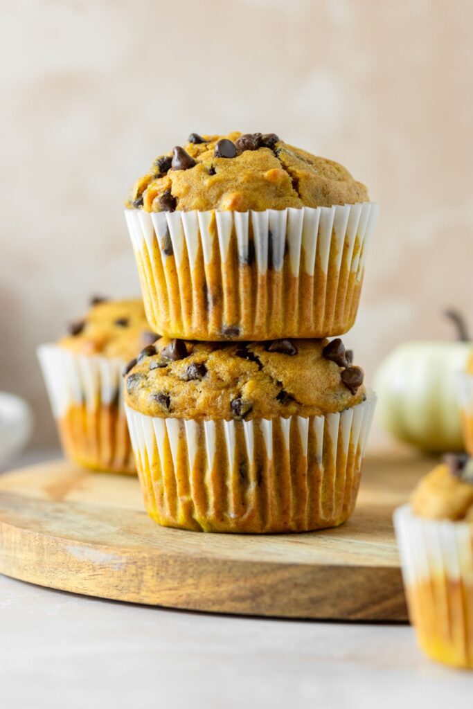 Two muffins stacked on top of each other sitting on a brown serving plate.