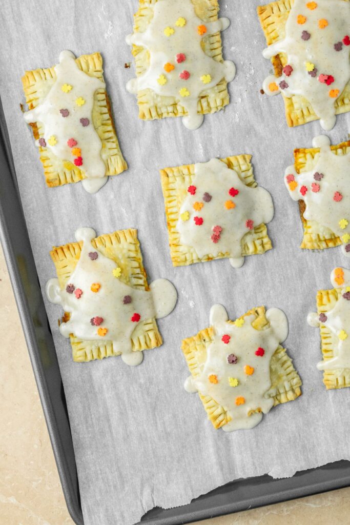 Homemade toaster pastries iced and decorated on a parchment paper lined baking sheet.