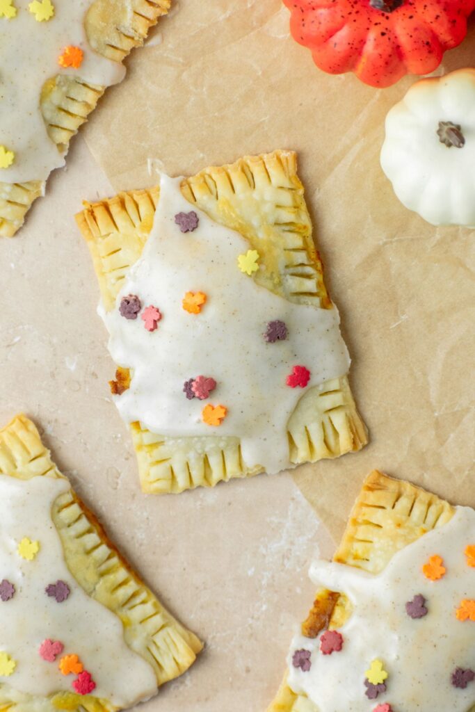 Four toaster pastries with a sweet icing on top. They're sitting on a piece of brown parchment paper.