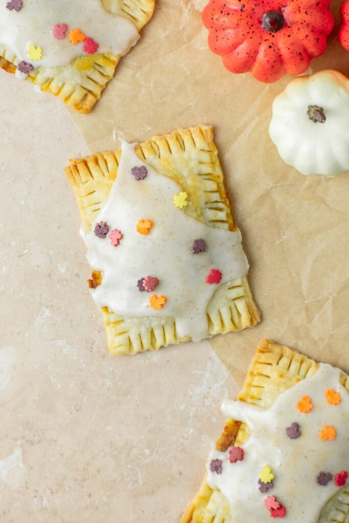 Pumpkin pop tarts with icing and leaf sprinkles on top.