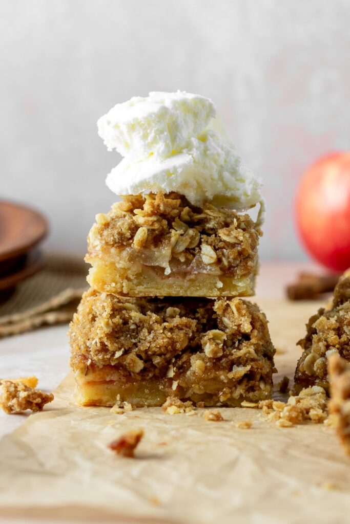 Two apple pie bars stacked on top of each other with a scoop of vanilla ice cream on top.