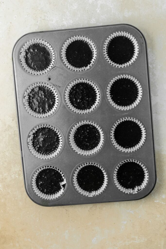 Chocolate cupcake batter in a muffin pan.