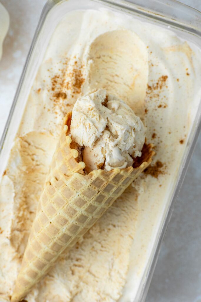 A waffle cones laying on top of no churn pumpkin ice cream.