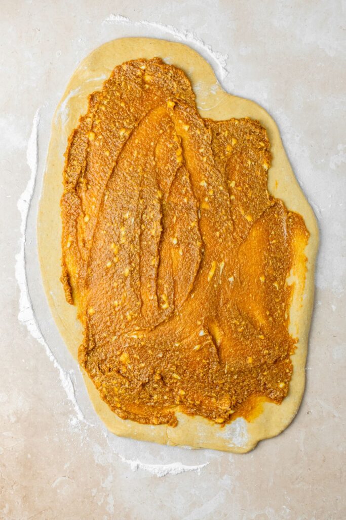 Rolled out dough with a pumpkin filling spread in the middle.