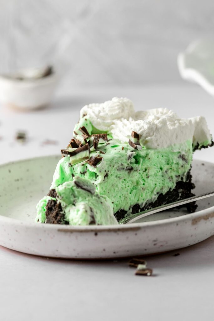 Andes mint pie slice on a plate with a fork taking a bite out of it.