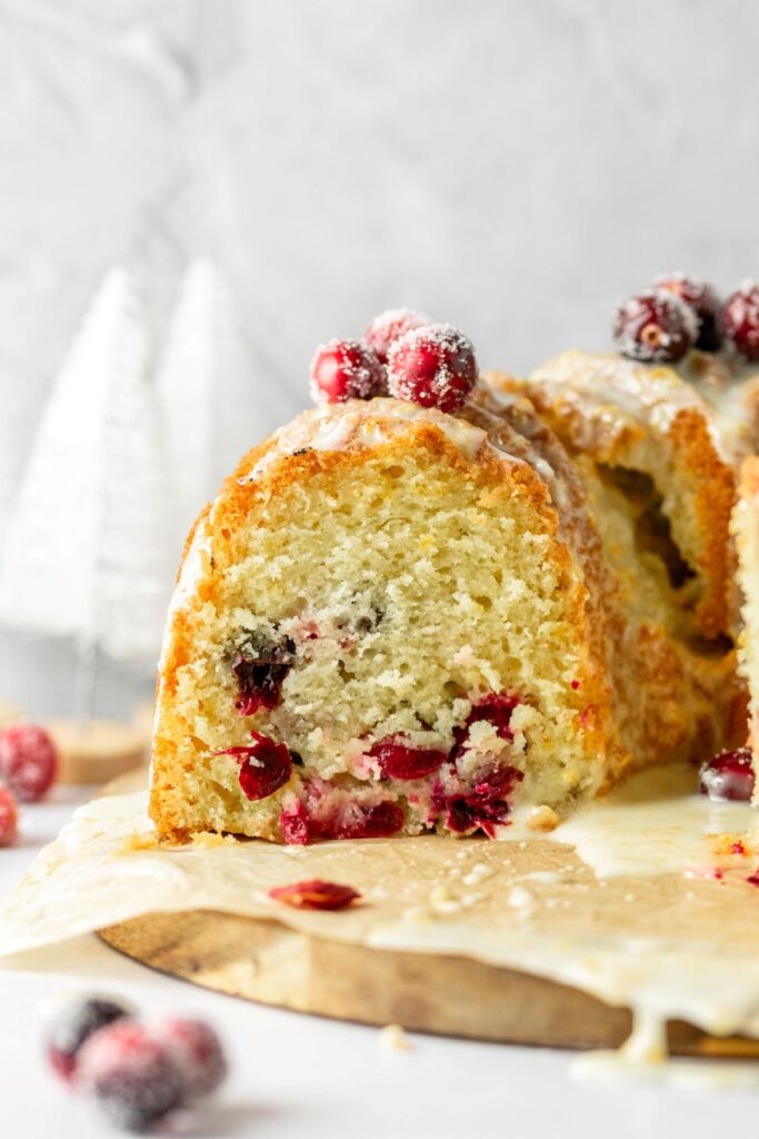Cranberry bundt cake with fresh cranberries on a brown piece of parchment paper.