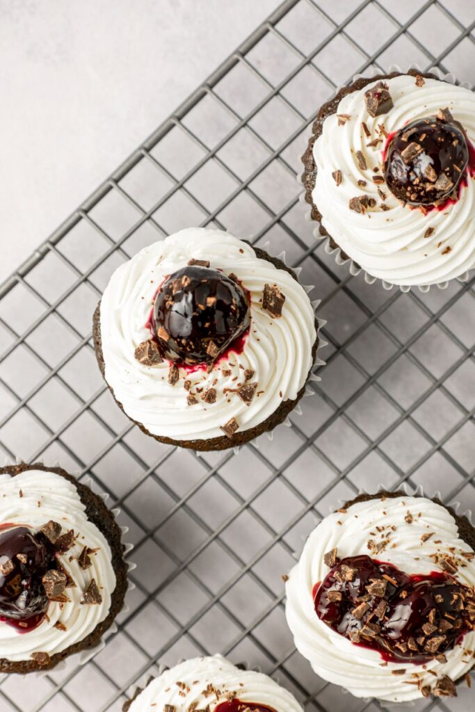 Cupcakes topped with whipped cream frosting, a cherry, and chocolate shavings.
