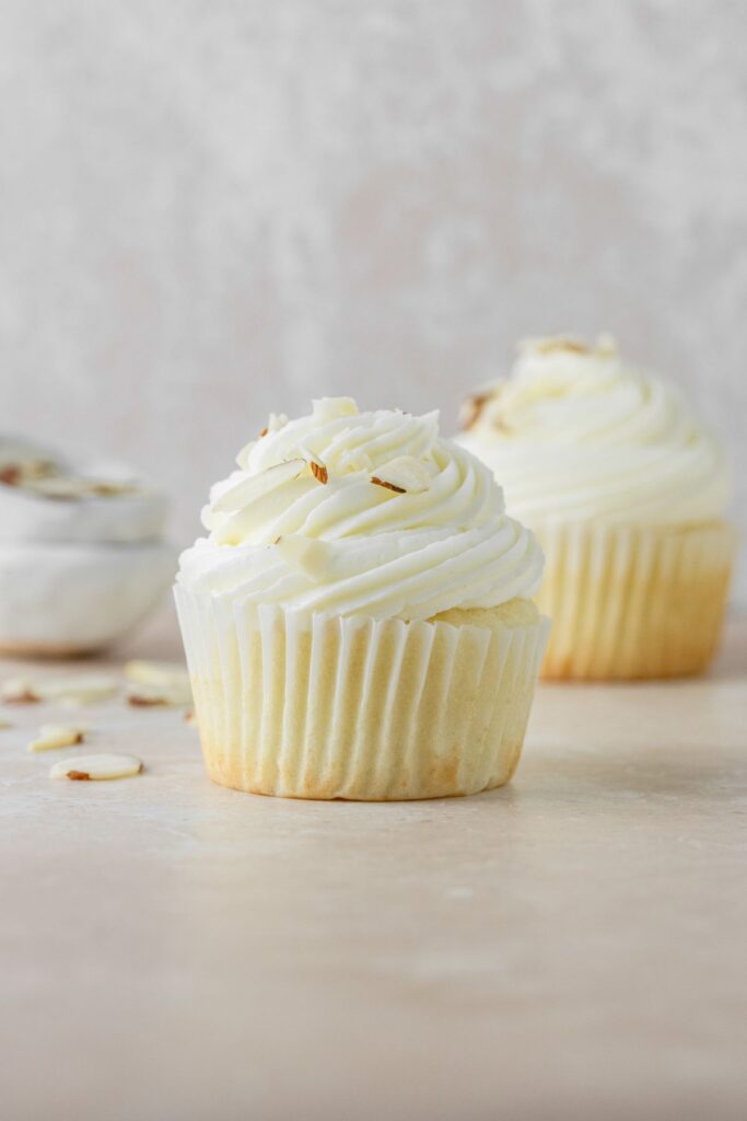 Almond cupcakes with almond buttercream frosting and sliced almonds on top.