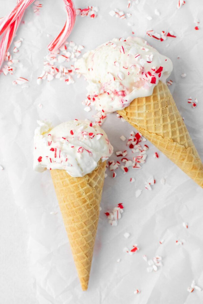 Two peppermint ice cream cones laying on parchment paper.