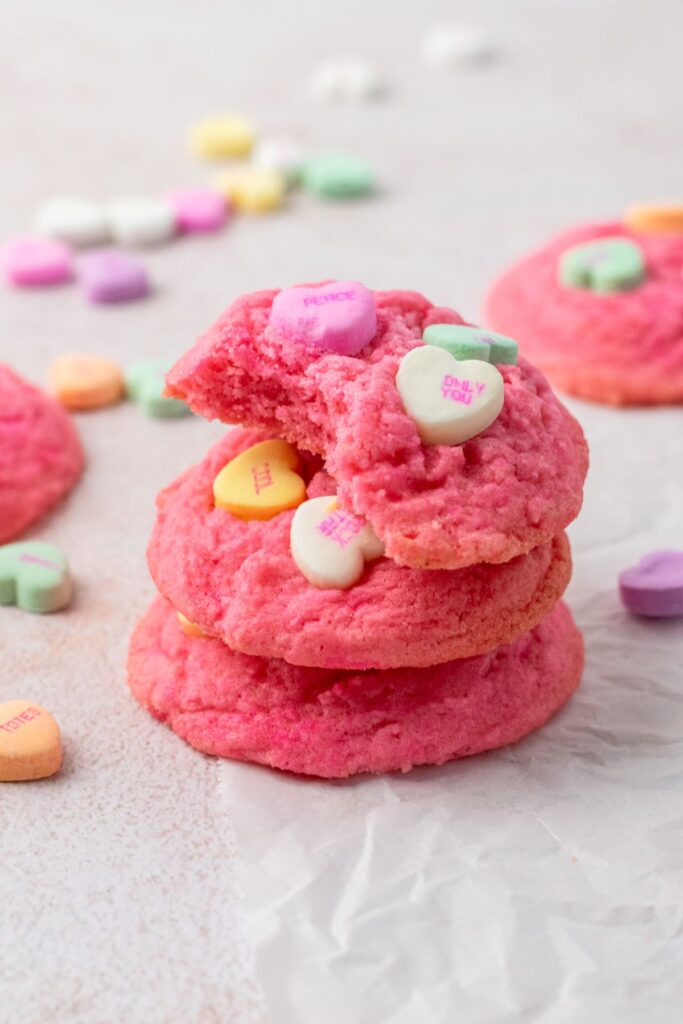 Stacked pink sugar cookies with conversation heart candies in them.