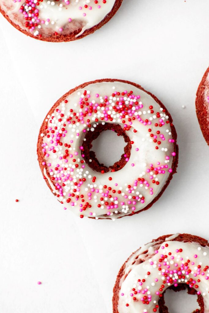 Valentine's day donuts covered in cream cheese frosting and sprinkles.