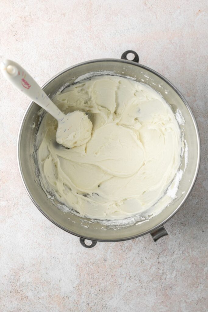 Cream cheese frosting in a bowl with a rubber spatula.