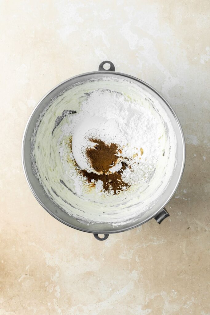 Powdered sugar and espresso powder added to a bowl to make frosting.
