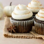 Pumpkin spice latte cupcakes with warm spices and white pumpkins in the background.