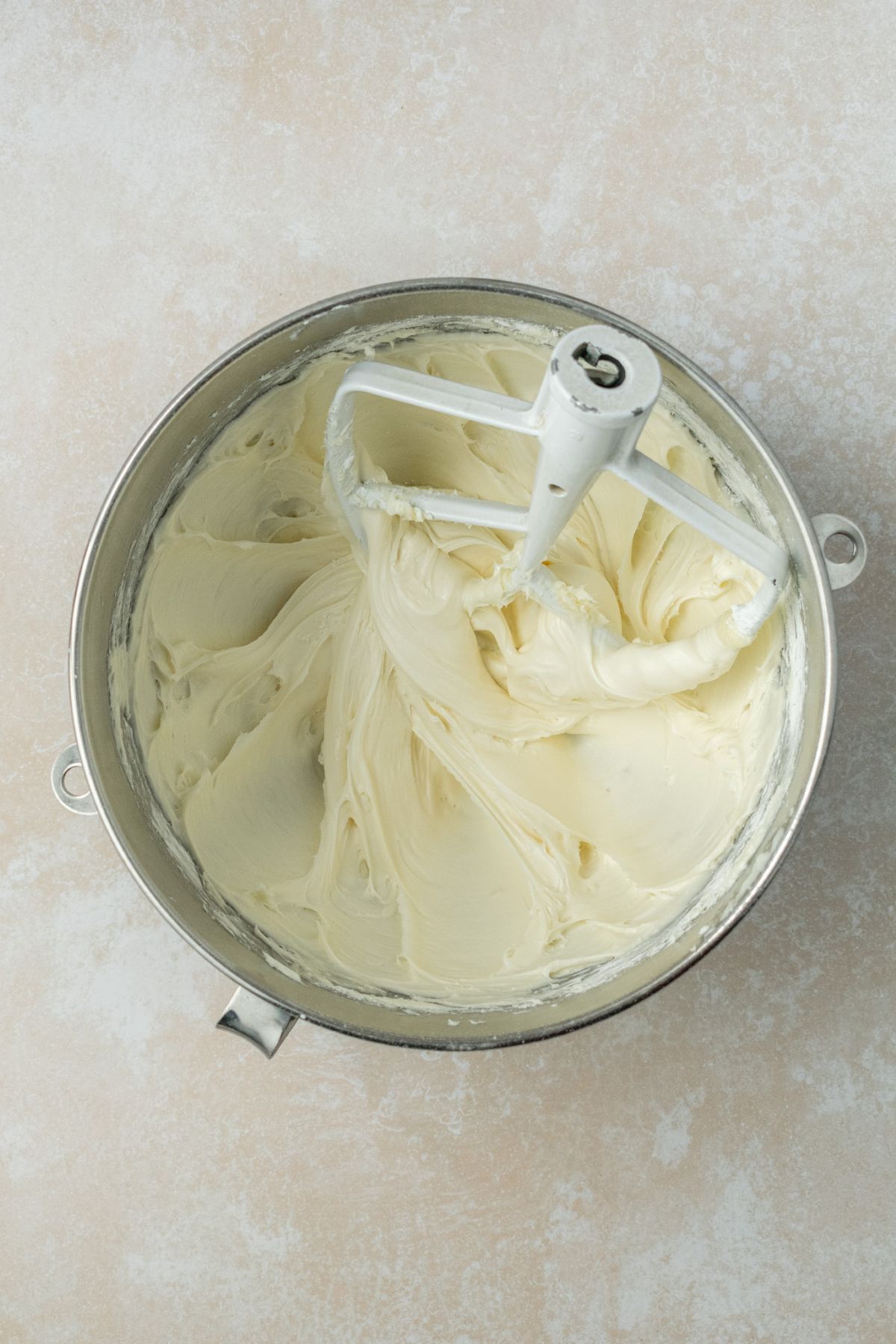 Cream cheese frosting in a bowl with a paddle attachment.