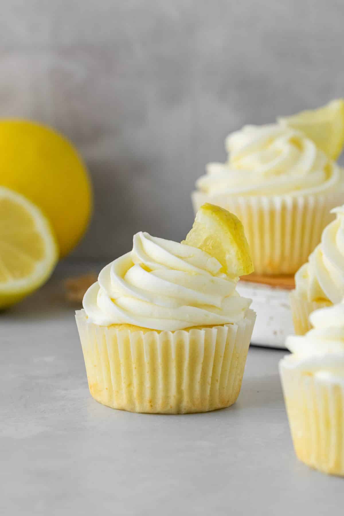 Homemade lemon cupcakes with lemon frosting and fresh lemons.