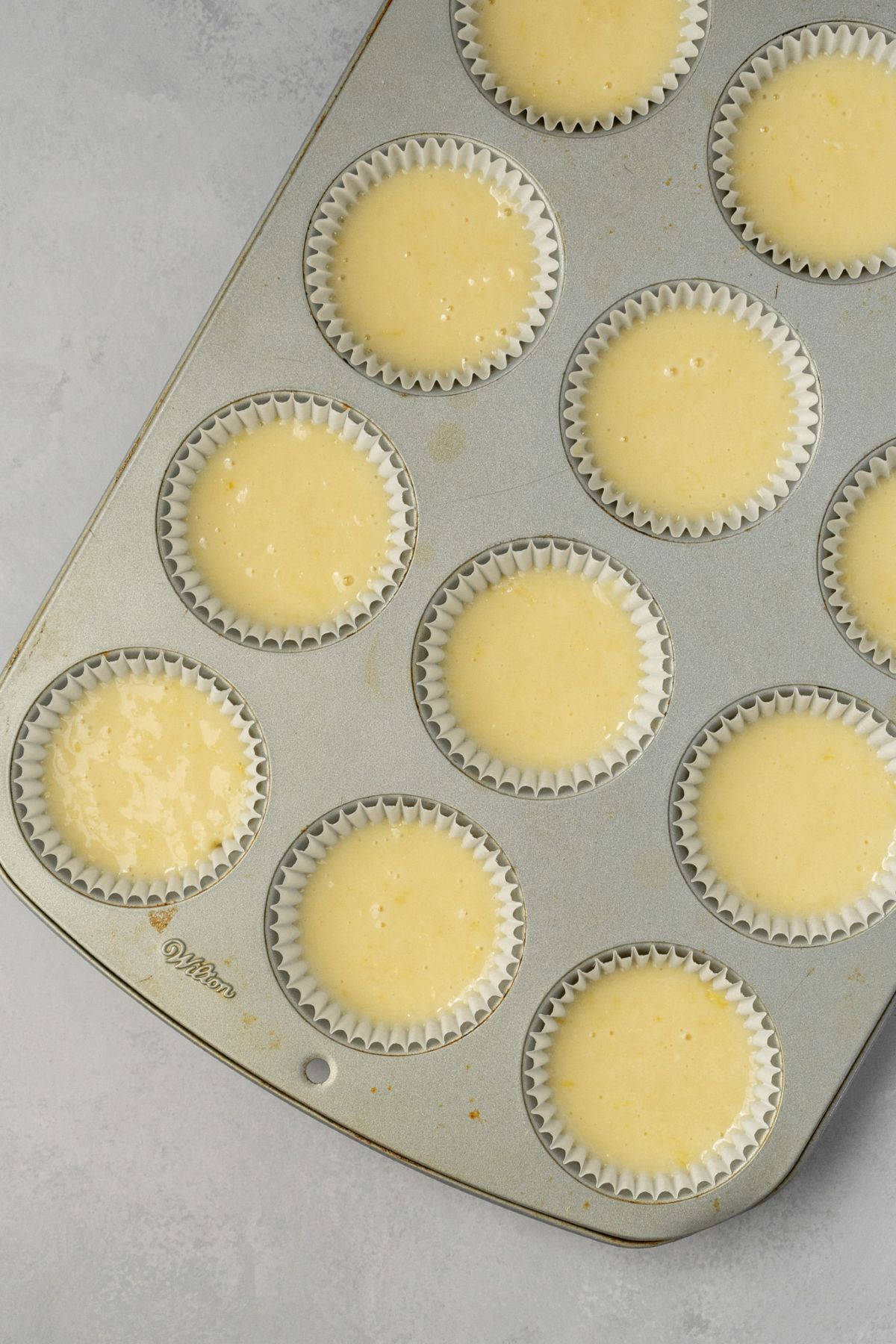 Muffin pan filled with cupcake liners and lemon cake batter.