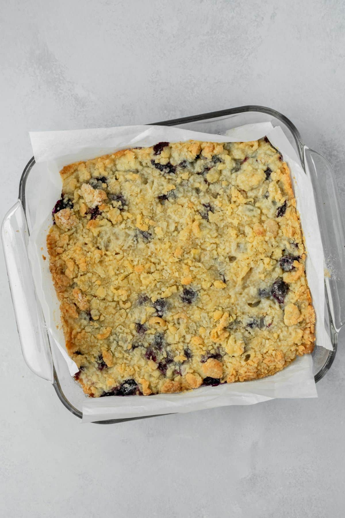 Baked blueberry pie bars cooling in a glass pan.