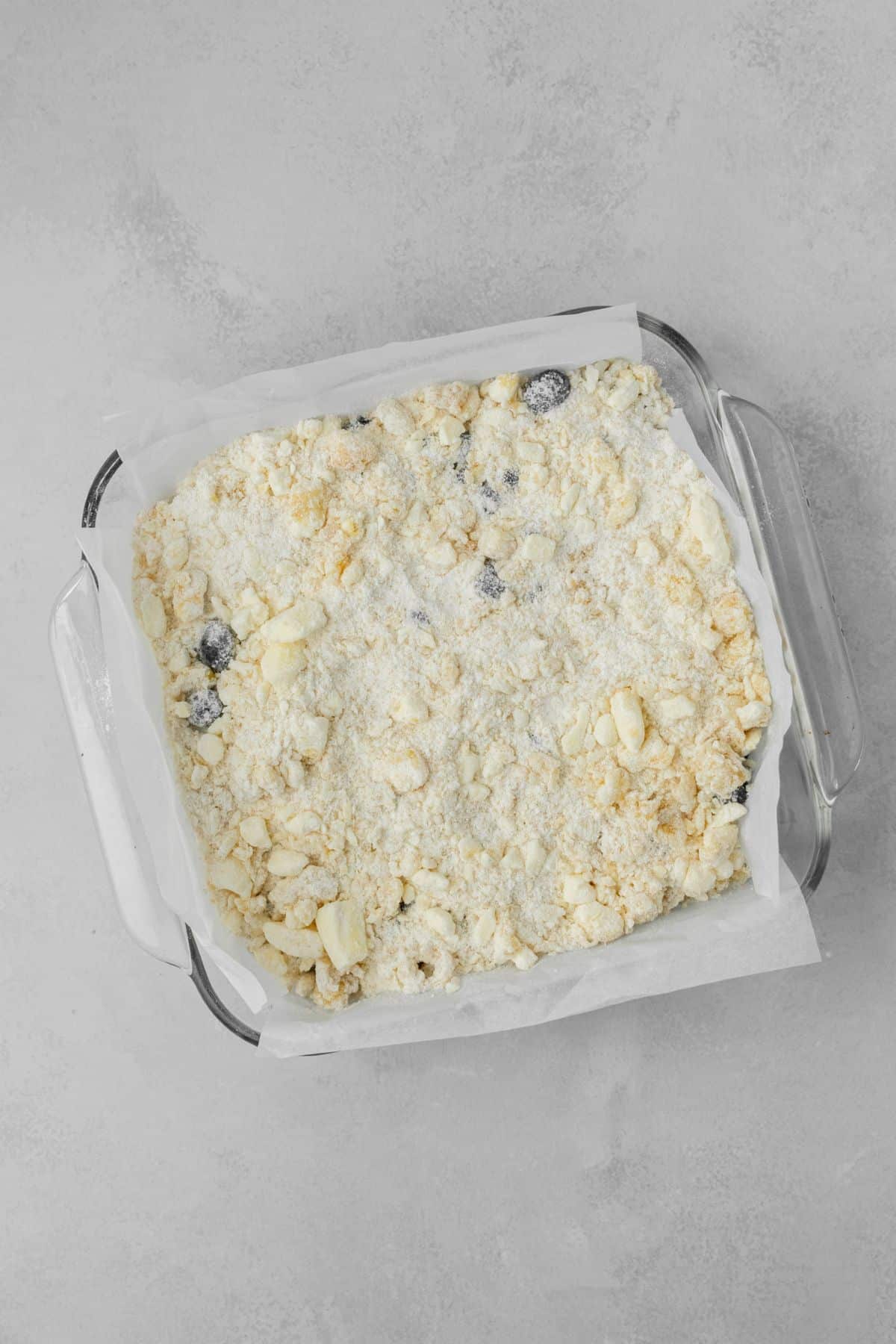 Blueberry pie bars in a glass baking pan ready to be baked.
