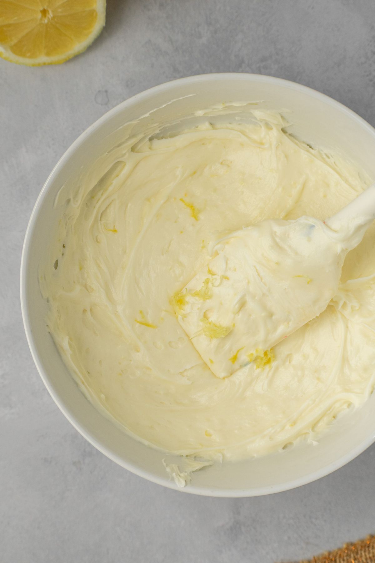 Easy lemon cream cheese frosting in a bowl with a rubber spatula.