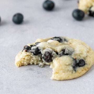 A bite taken out of a chewy blueberry white chocolate cookie.