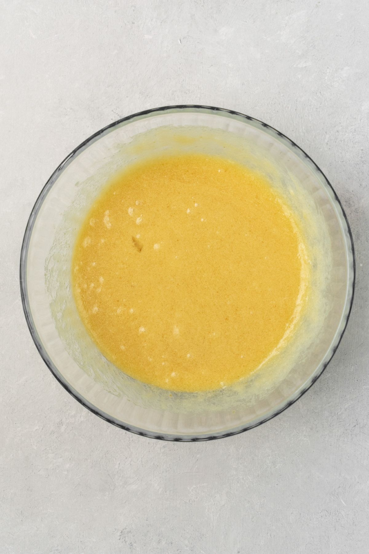 Wet ingredients that have been whisked together for cookies in a glass bowl.