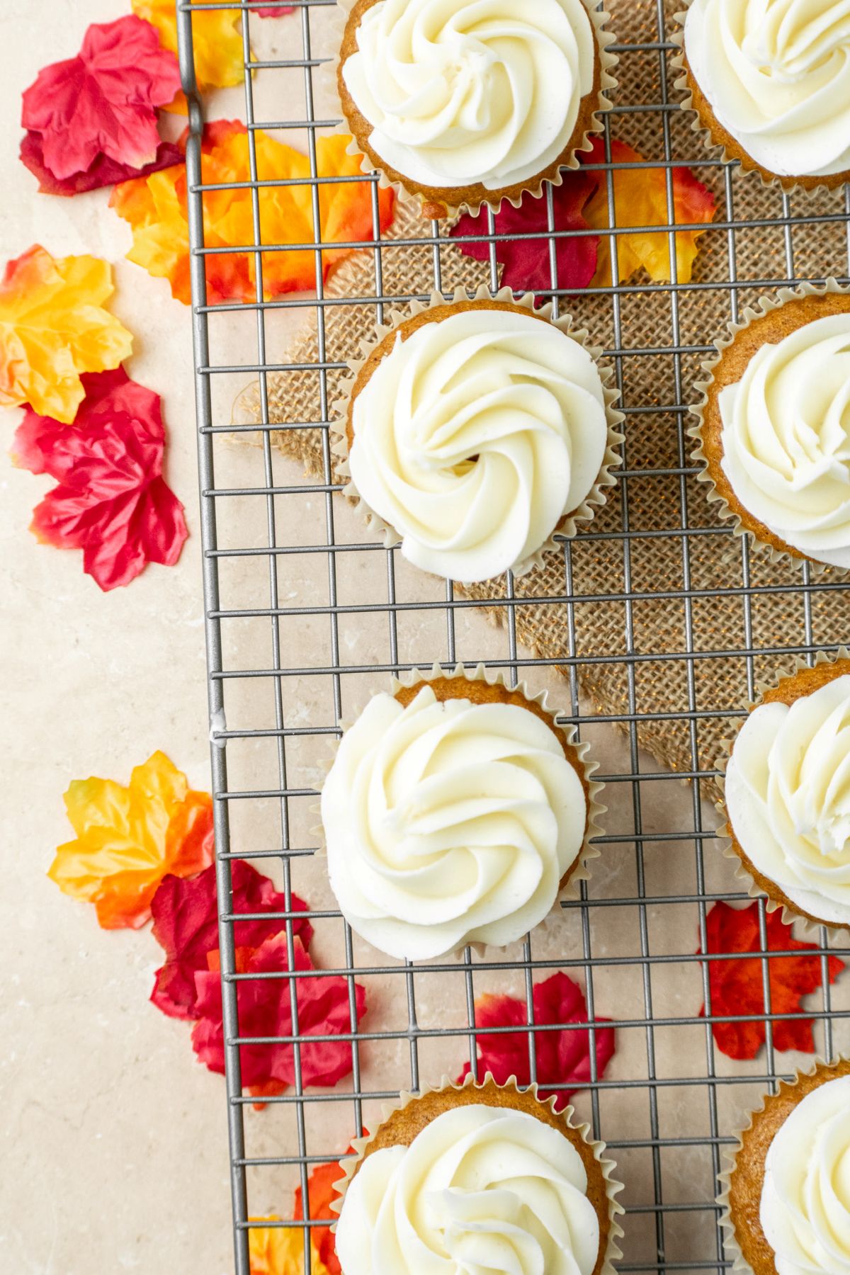 Maple frosted pumpkin cupcakes that are on top of a wire cooling rack.