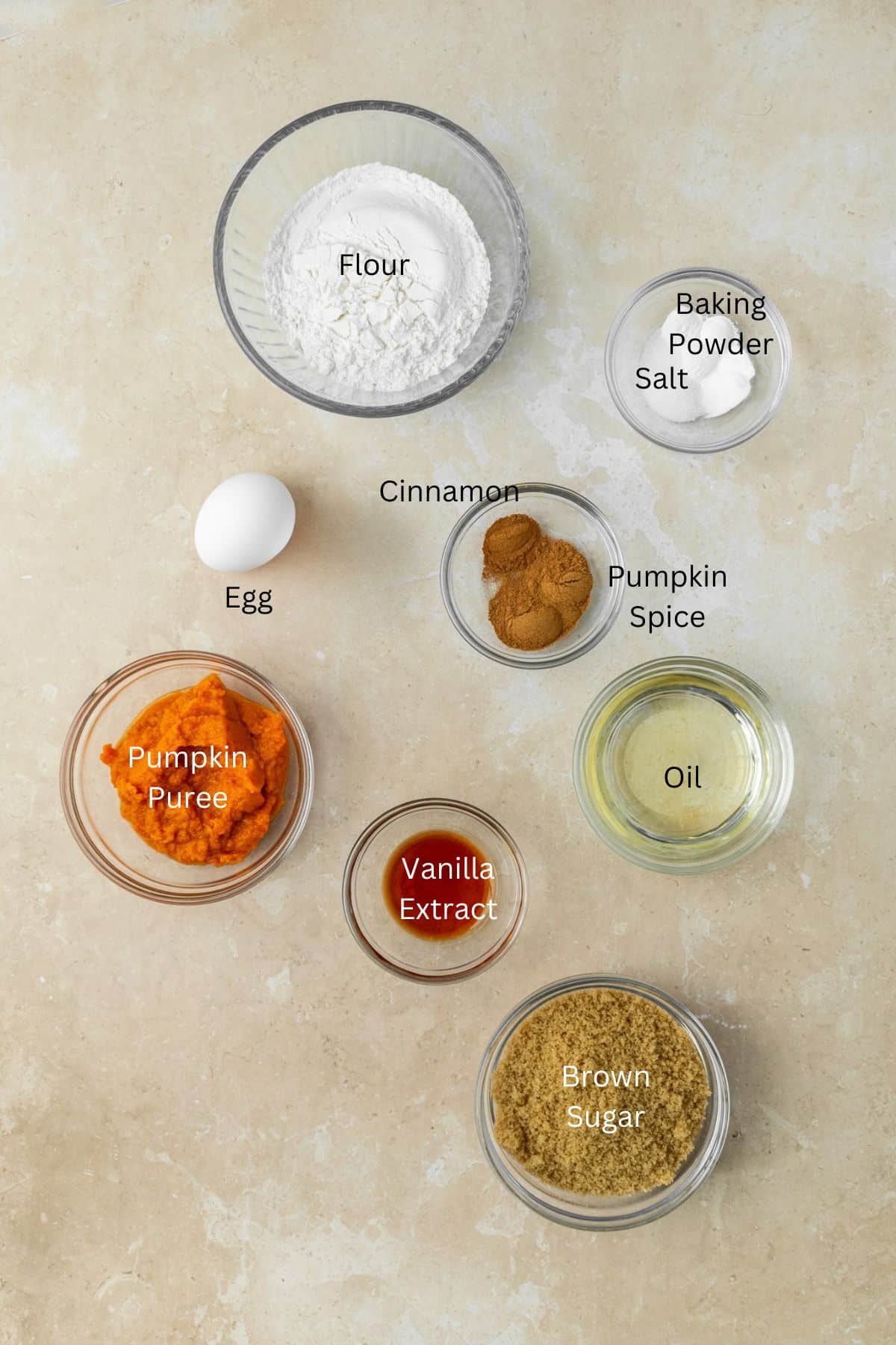 Ingredients for pumpkin cake: flour, egg, baking powder, salt, cinnamon, pumpkin spice, pumpkin puree, brown sugar, oil, and vanilla.