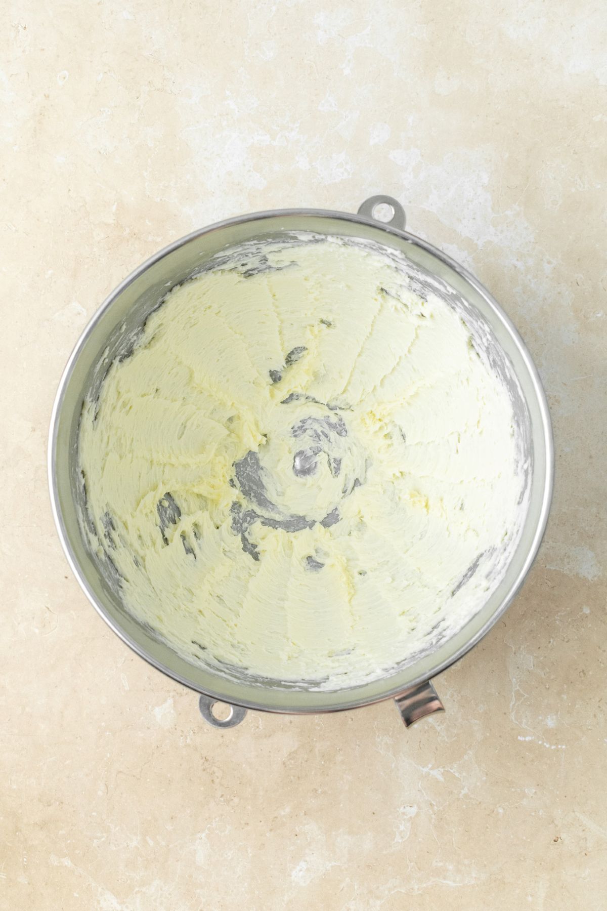 Creamed butter for frosting in a large stainless steel bowl.