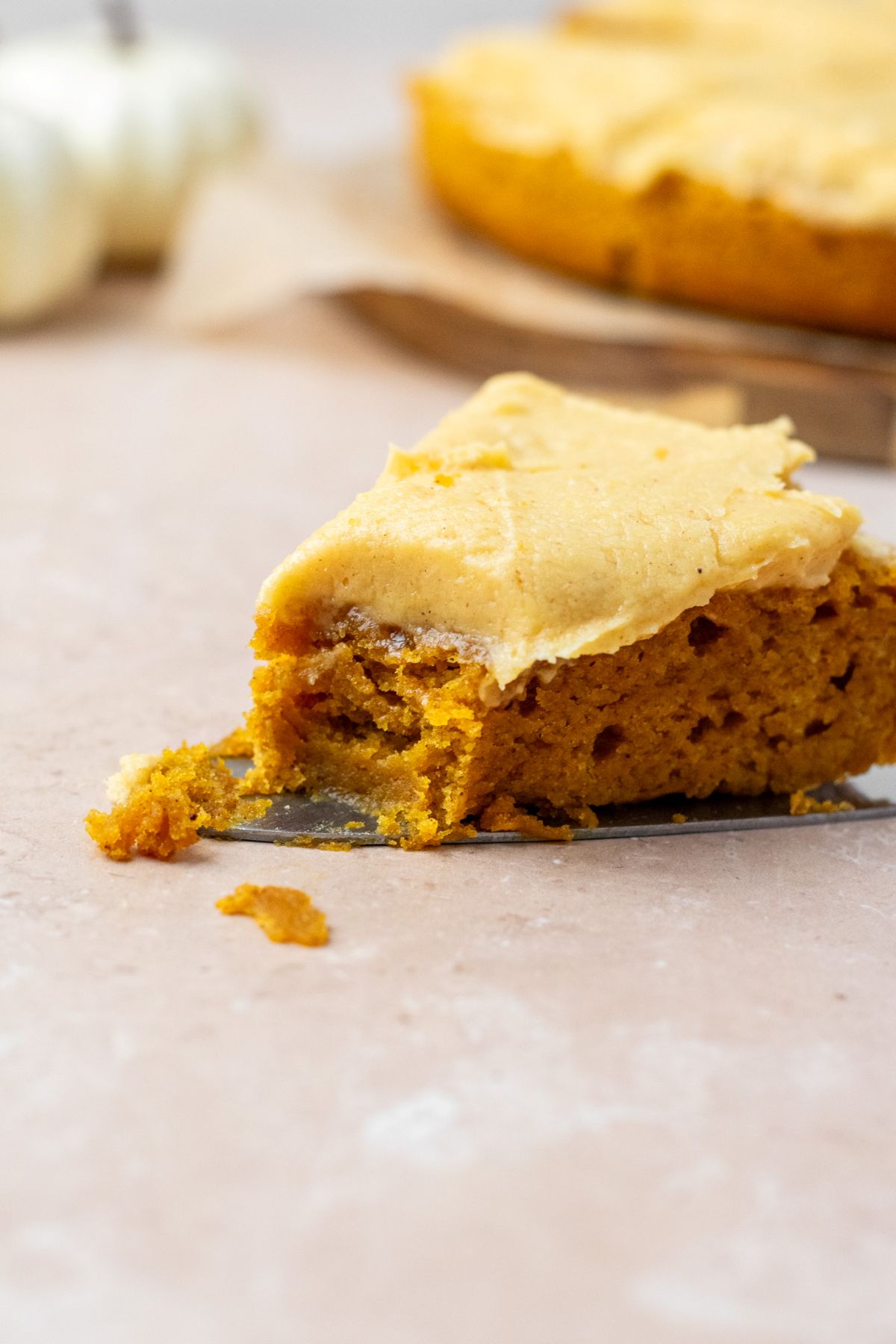 A slice of moist pumpkin cake topped with frosting and a bite taken out of it.