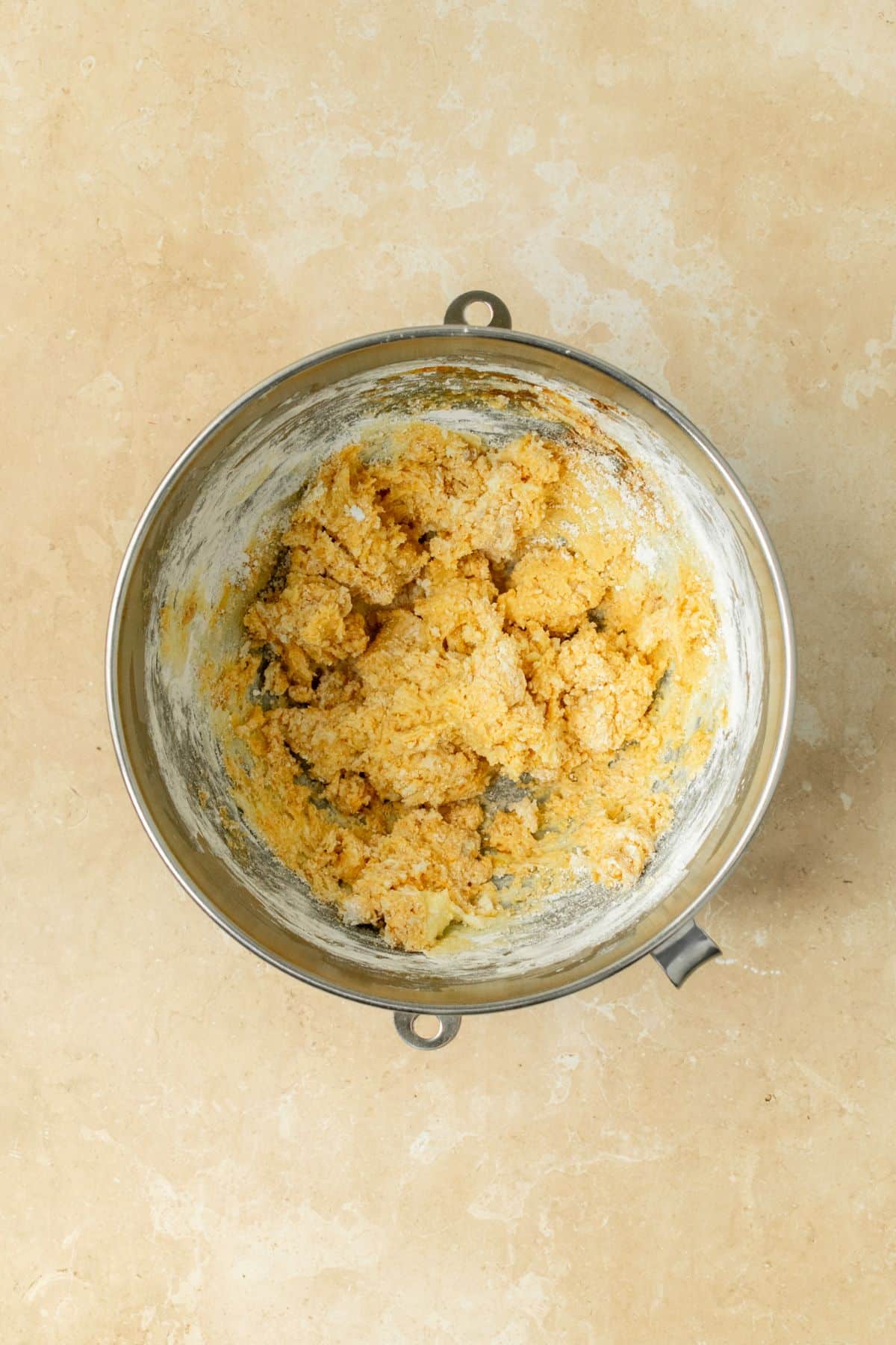 Ingredients for pumpkin frosting clumped together in a stand mixer bowl.