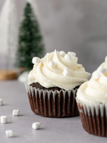 Hot cocoa cupcakes with marshmallow frosting and mini marshmallows on top.
