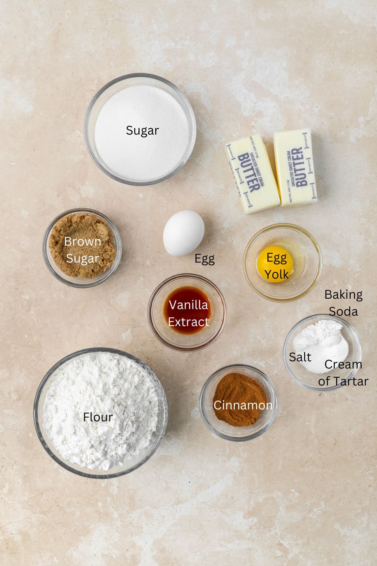 Ingredients for snickerdoodles: sugar, brown sugar, butter, egg, egg yolk, vanilla, flour, cinnamon, salt, baking soda, and cream of tartar.